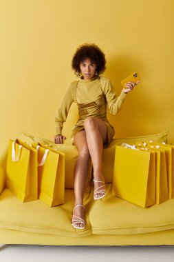 Parlak renkli stüdyo, alışveriş torbaları arasında akıllı telefon tutan şık bir kadını sergiliyor..
