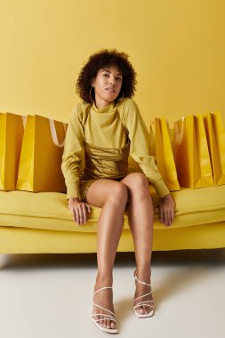 Parlak stüdyo sarı renkli kıvırcık saçlı, alışveriş torbalarıyla çevrili bir kadın barındırıyor..