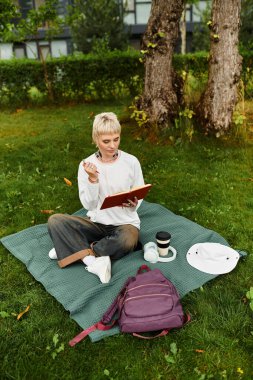 Genç bir kadın parkta bir battaniyenin üzerinde oturuyor, doğası gereği güzelliklerle dolu, yazılı bir şekilde..