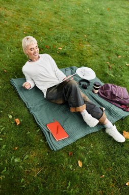 Parlak güneşli bir günde parkta eğlenen genç bir kadın bulur. Yazar ve kahvesini yudumlar..