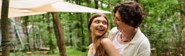 Genç bir çift, yemyeşil bir ortamda rahatlarken neşeli bir kahkaha atar, sevgiyi kucaklarlar..