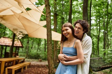 Sevgi dolu çift, doğal güzelliklerle dolu huzurlu bir ormanlık alanda dinlenirken aynı neşeli kucaklaşmayı paylaşıyor..