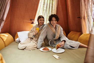 Sevgi dolu bir çift keyifli bir kahvaltıyı paylaşırken rahat elbiseler giyer, neşe saçar.