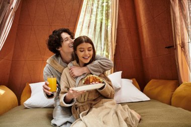 Huzurlu bir ortamda, genç bir çift rahatlarken kahkaha ve lezzetli yemekleri paylaşır..