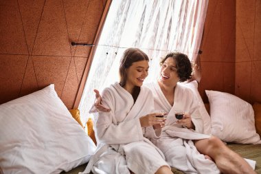 Yumuşak cüppeli iki genç aşık gülüyor ve loş bir mekanda sıcak içkilerin tadını çıkarıyor..