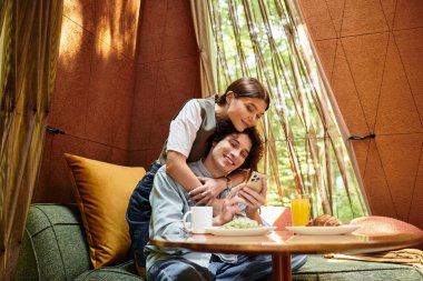 Genç çift birlikte eğlenirken aynı anda gülümseme ve tatlı bir atıştırmalık paylaşıyorlar..