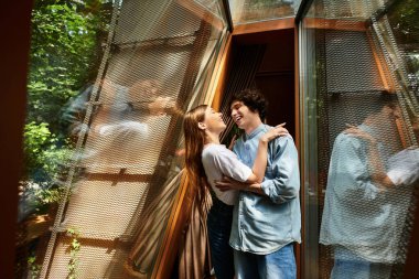 İki genç insan mutlu bir kucaklaşmayı paylaşıyor, sakin bir park ortamında zamanlarının tadını çıkarıyorlar..