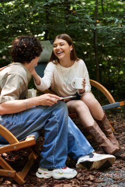 Genç bir çift parkta oturur, keyifli bir anı paylaşırken içkilerini yudumlar ve güneşte gülümserler..