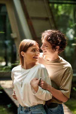 Genç çift parkta kucaklaşır, birlikte geçirdikleri zamanı sevgiyle ve kahkahalarla kutlarlar..