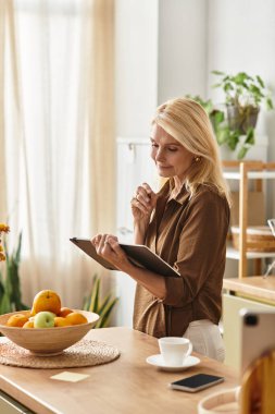 Sevimli bir son sınıf öğrencisi mutfakta meyve dolu bir tablet okurken gülümsüyor..