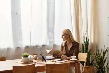Son sınıf öğrencisi bir masada oturmuş kitap okuyor ve sessiz sakin bir mekanda sıcak bir içkinin tadını çıkarıyor..