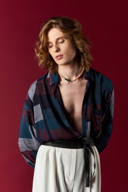 Şık bir adam cesur bir arkaplana karşı özgüvenle poz verir, modern modayı somutlaştırır..