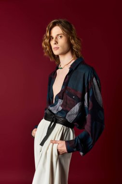 Şık bir genç adam, kalın bir gömlek ve özel dikim pantolon giyer ve poz verir..