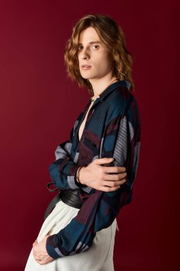 Genç bir adam büyüleyici bakışlarıyla çekici tarzını sergiliyor. Zarif ve modaya uygun giysiler giyiyor..