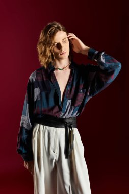 Genç bir adam zarif bir stil sergiliyor. Dinamik bir pozda kadınsı ve modaya uygun elementlerin karışımı..