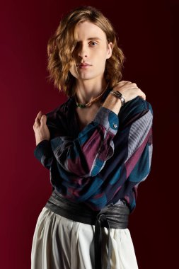 Çarpıcı bir genç adam cesur moda seçimlerinde ve büyüleyici duruşunda sersemletir..