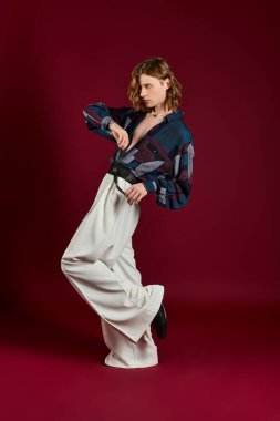 Çabasız bir şekilde stil sahibi genç bir adam poz veriyor, modaya uygun bir görünüm ve cesur moda seçimleri sergiliyor..