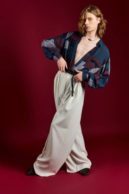 Genç bir adam, kendine güveni bol pantolon ve kalın bir gömlek giyer, eşsiz tarzını sergiler..