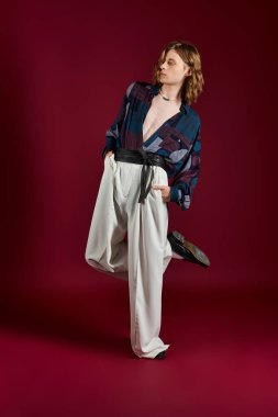 Şık bir genç adam çarpıcı bir arka plana karşı duruyor, modern moda sergiliyor..