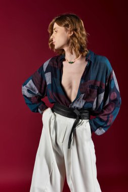 Çarpıcı bir genç adam renkli bir elbise içinde cesur bir arka plana karşı güven içinde poz veriyor..