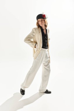 Kendine güvenen genç bir adam şık bir beyaz takım elbise ve siyah gömlekle cazibesini sergiliyor..