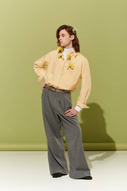 Yakışıklı genç bir adam, kendine güvenen bir şekilde kendine özgü, kadınsı bir şekilde poz verir..