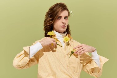 Şık, açık sarı bir kıyafet giyen şık adam, çiçeklerle çarpıcı bir görünüm sergiliyor..