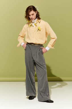 Pastel gömlekli, geniş pantolonlu, çiçekli, kendinden emin genç bir adam..