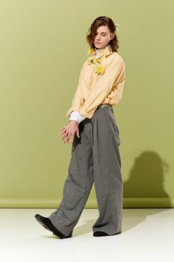 Tarz sahibi genç bir adam, yumuşak bir arka planda poz verir..