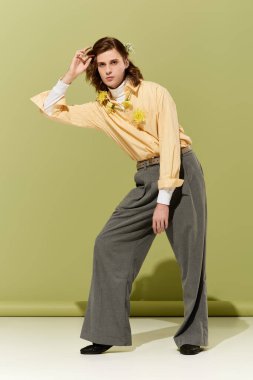 Tarz sahibi genç bir adam, yaratıcılık ve moda eğilimlerini ifade eden kadınsı bir kıyafet içinde zarif bir şekilde poz verir..