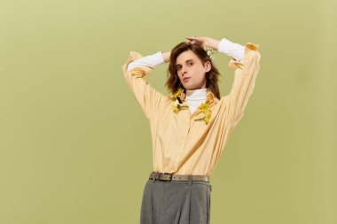 Bu şık insan, soluk yeşil bir zemine karşı poz veriyor. Modayı belirleyen yetenekleri gösteriyor..