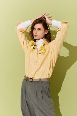 Yakışıklı genç adam çiçek aksanlı şık bir kıyafet içinde poz veriyor, kendine güven ve tarz yayıyor..