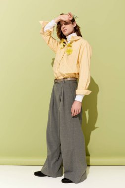 Çekici bir genç adam zarif bir şekilde poz veriyor yumuşak yeşil bir arka plana karşı..