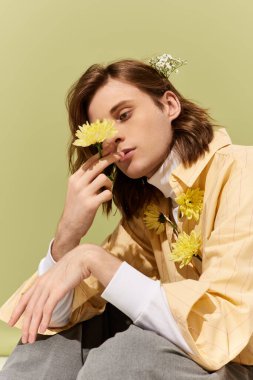 Şık bir genç adam zarif bir şekilde canlı bir ortamda çiçeklerle poz veriyor, zarafet sergiliyor..