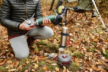 Huzurlu bir orman ortamında, yaşlı bir kadın doğayla iç içe iken sıcak bir yemek hazırlar..