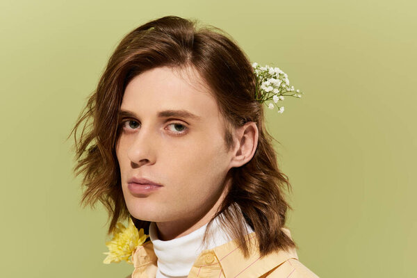 Stylish young man with flowing hair shows a modern look amid vibrant blooms.