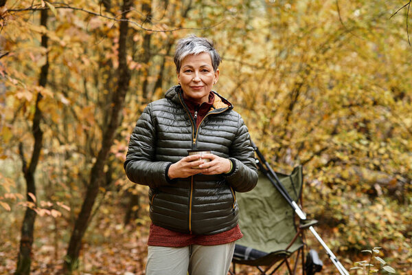 Старшая женщина находит покой, путешествуя в ярком осеннем лесу.
