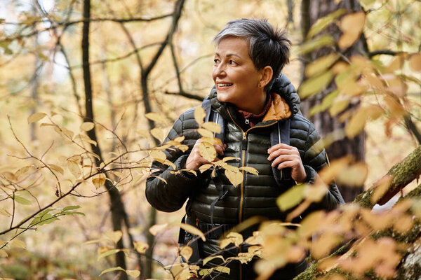 Senior woman enjoys hiking through a serene forest filled with vibrant autumn colors.