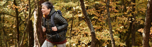 A senior woman enjoys a refreshing hike through the colorful forest during autumn.