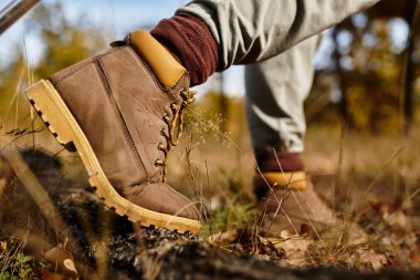 Yaşlı bir kadın orman yolunda kendinden emin adımlar atar, doğanın güzelliğini takdir eder..