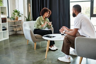 Modern bir stüdyoda bir erkek ve kadın görüşlerini paylaşıyor ve gülümsüyor..