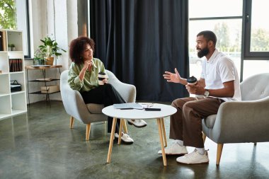 Bir kadın ve bir erkek modern bir stüdyo ortamında röportaj yapıyorlar..