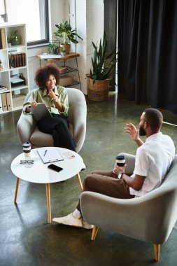 Genç bir kadın ve erkek şık bir stüdyoda dostça bir röportaj yapıyorlar..