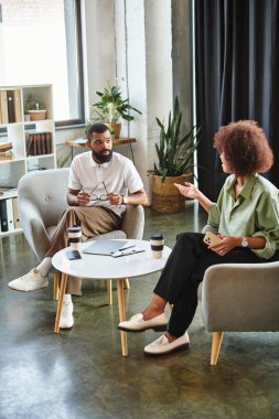 Genç bir kadın ve erkek bitkilerle dolu şık bir stüdyoda röportaj yapıyorlar..