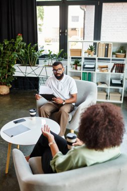 İki genç profesyonel, bitkilerle dolu çağdaş bir stüdyoda röportaj yapıyorlar..
