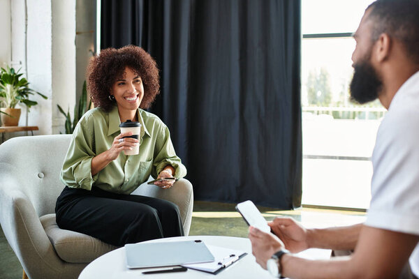 A woman and man participate in a interview, sharing smiles and discussion over coffee.