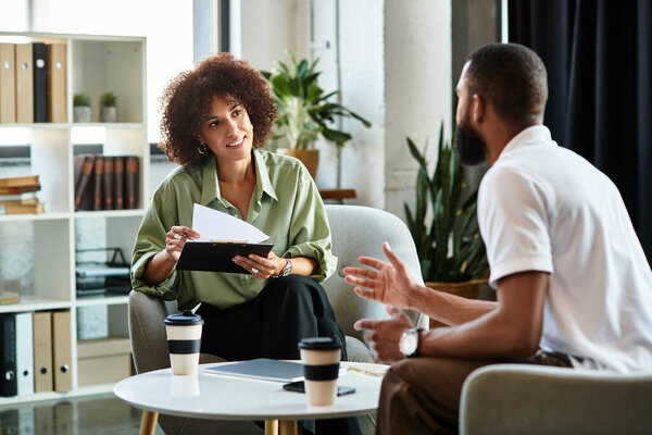 Young woman interviews a man in a contemporary studio with stylish decor and greenery.