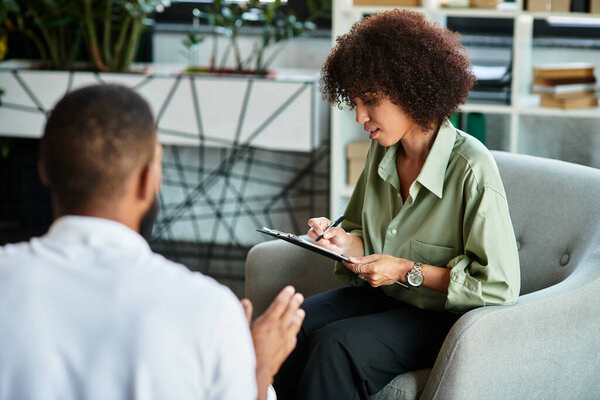 A young woman interviews in a modern studio, taking notes and listening intently.