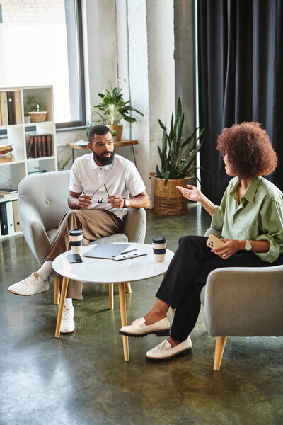 Молодая женщина и мужчина берут интервью в стильной студии, наполненной растениями.