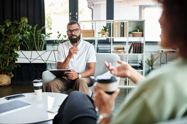 A young man listens attentively as a woman shares her thoughts in a contemporary studio.